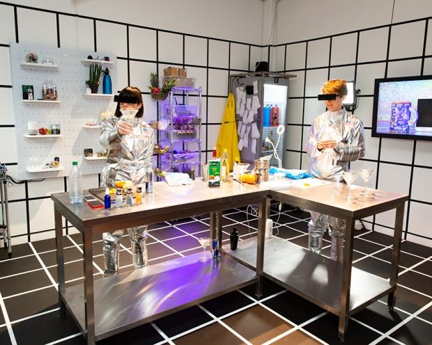 TWO INDIVIDUALS MAKE COCKTAILS IN FUTURISTIC KITCHEN THAT RESEMBLES A LAB IN EAT TECH KITCHEN