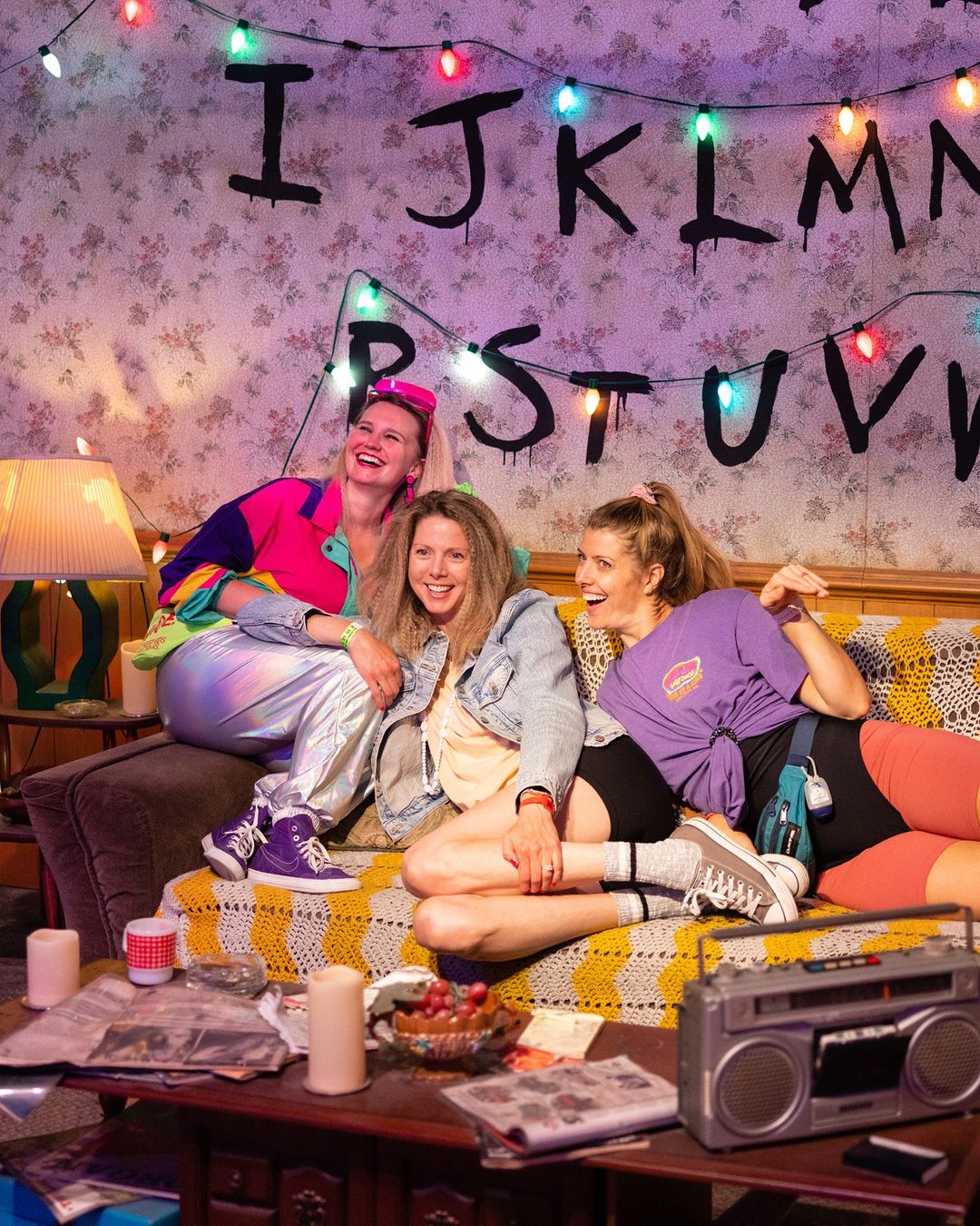 THREE GIRLS SITTING ON COUCH IN NETFLIX’S STRANGER THINGS: THE EXPERIENCE