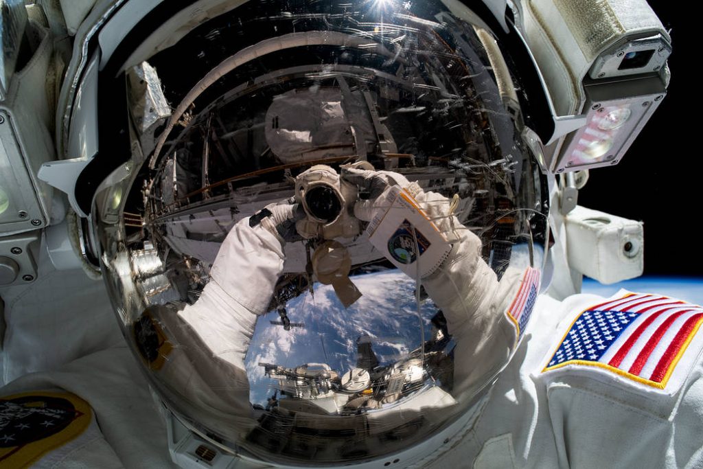 REFLECTION OF SPACE ON SPACE HELMET DURING IMMERSIVE EXPERIENCE CALLED THE INFINITE