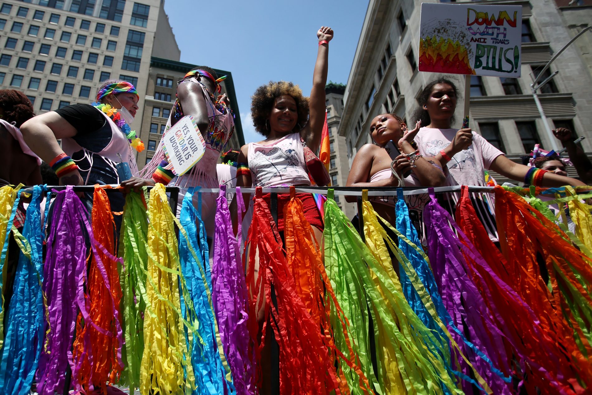 PEOPLE STANDING AND HOLDING UP SIGNS AT LGBTQIA+ PRIDE EVENT IN NYC