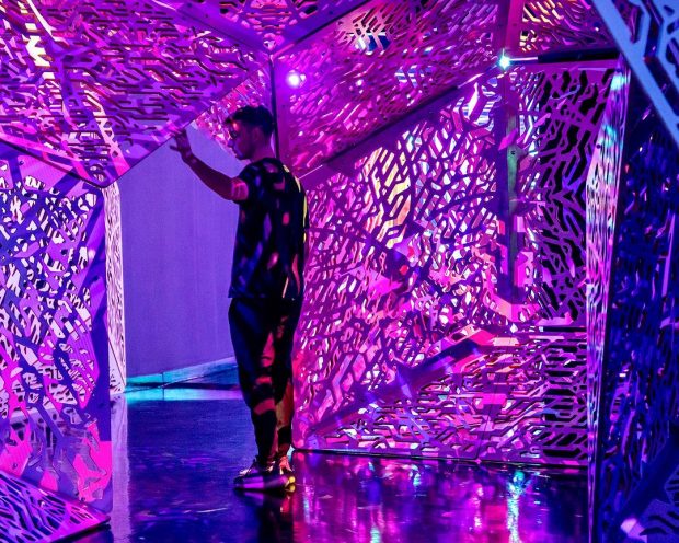 MAN STANDS IN DOORWAY OF PINK AND PURPLE IMMERSIVE ART INSTALLATION AT OTHERWORLD COLUMBUS