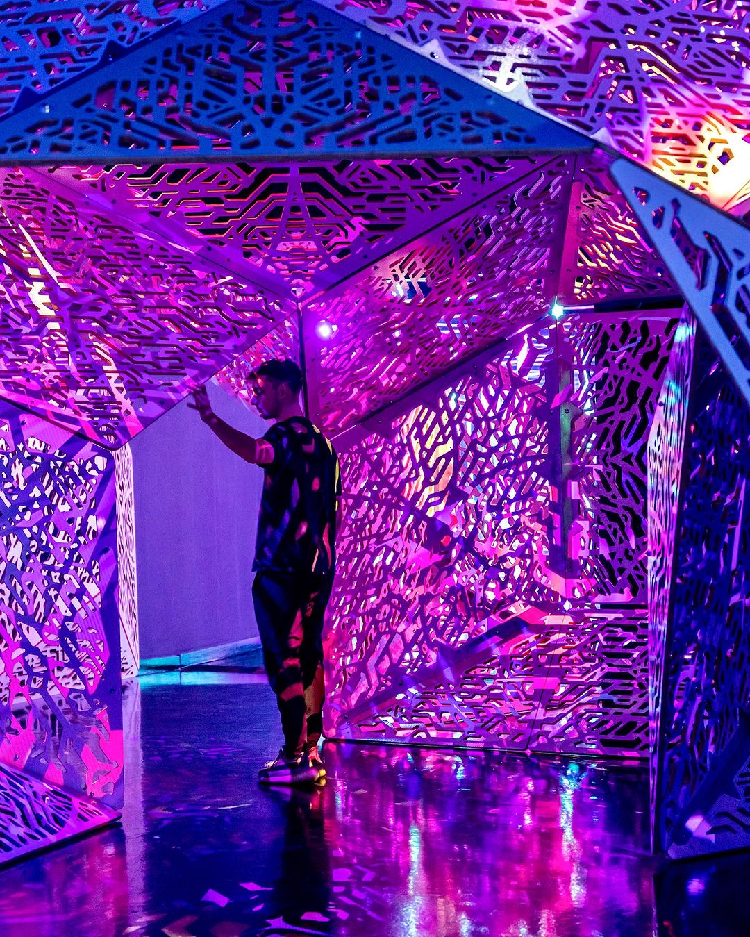 MAN STANDS IN DOORWAY OF PINK AND PURPLE IMMERSIVE ART INSTALLATION AT OTHERWORLD COLUMBUS