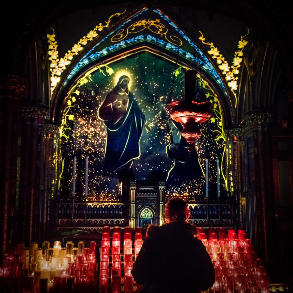 LIT UP INTERIOR OF THE NOTRE DAME BASILICA WITH CANDLES IN MONTREAL FOR MOMENT FACTORY’S AURA AT THE NOTRE DAME BASILLICA