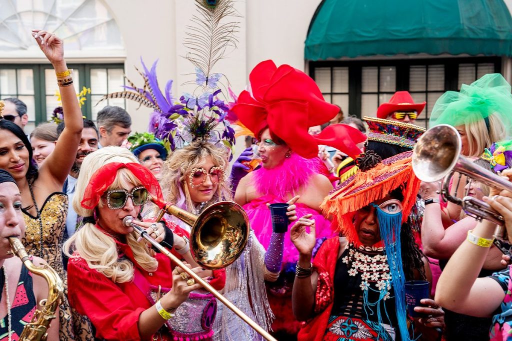 March XP: Colorful street parade with costumed musicians and revelers celebrating with brass instruments and vibrant outfits.