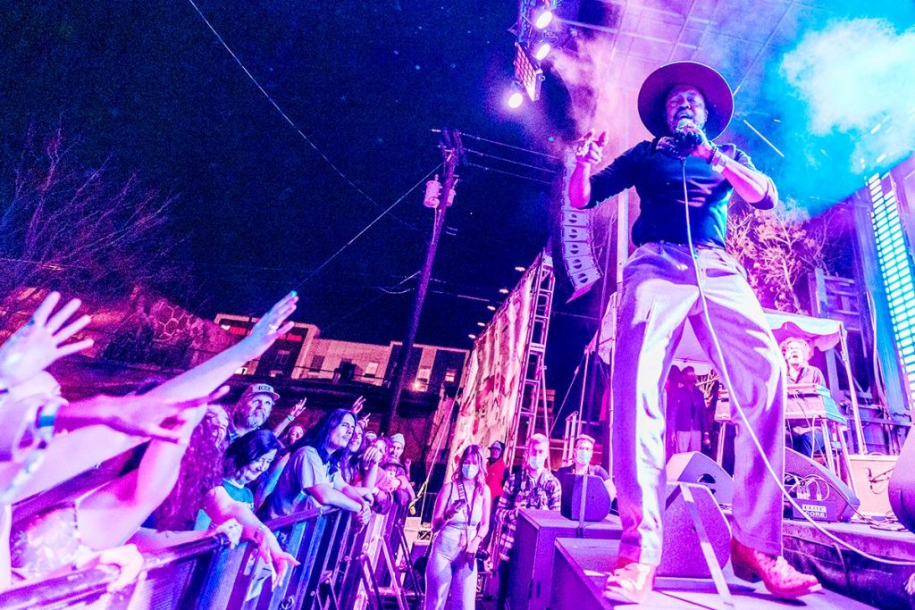 March XP: Dynamic nighttime concert scene with a performer engaging the crowd under colorful stage lighting.